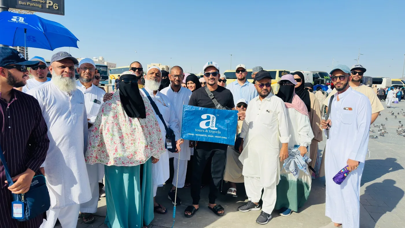 Azeem Tours pilgrims gathered around the blue Azeem flag in Madinah