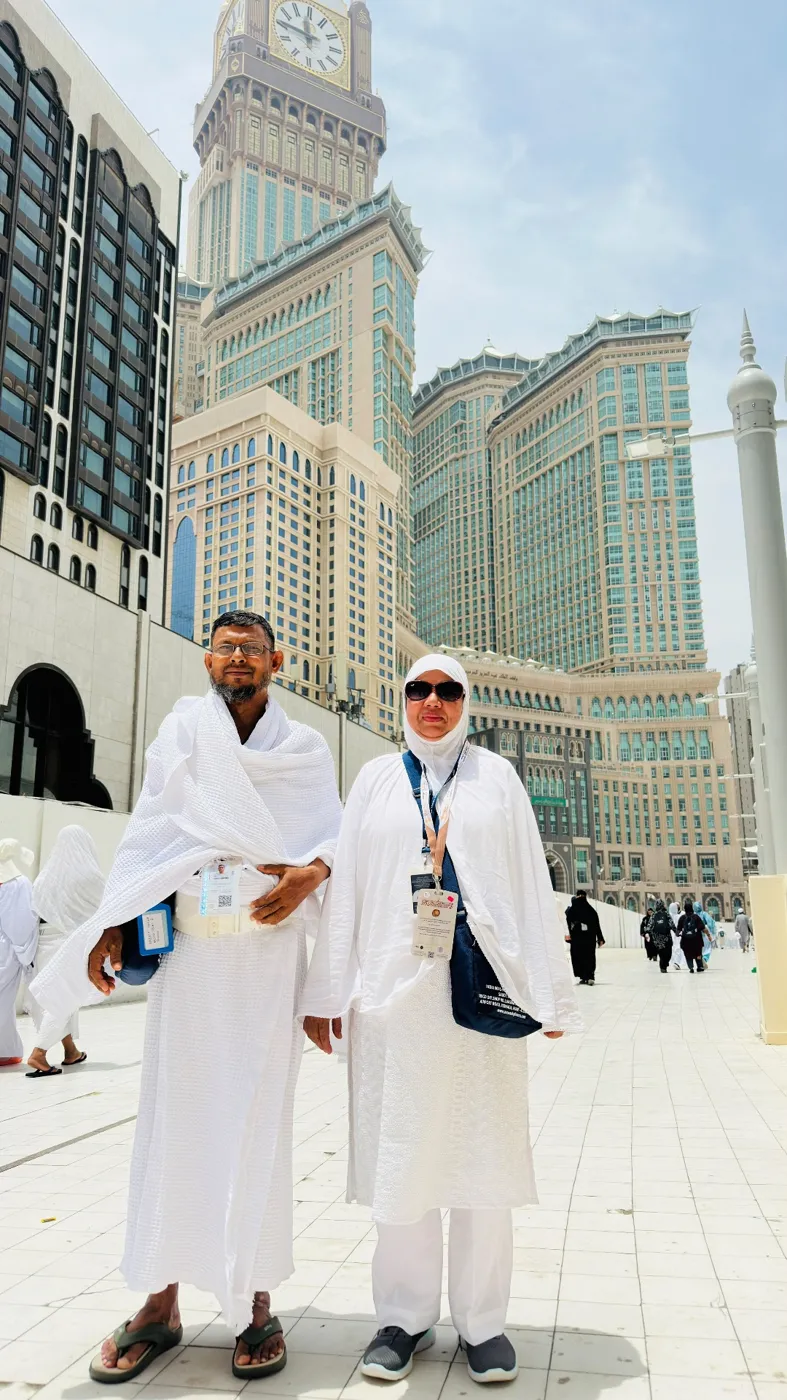 A pilgrim couple in white Ihram beneath the Makkah Clock Tower