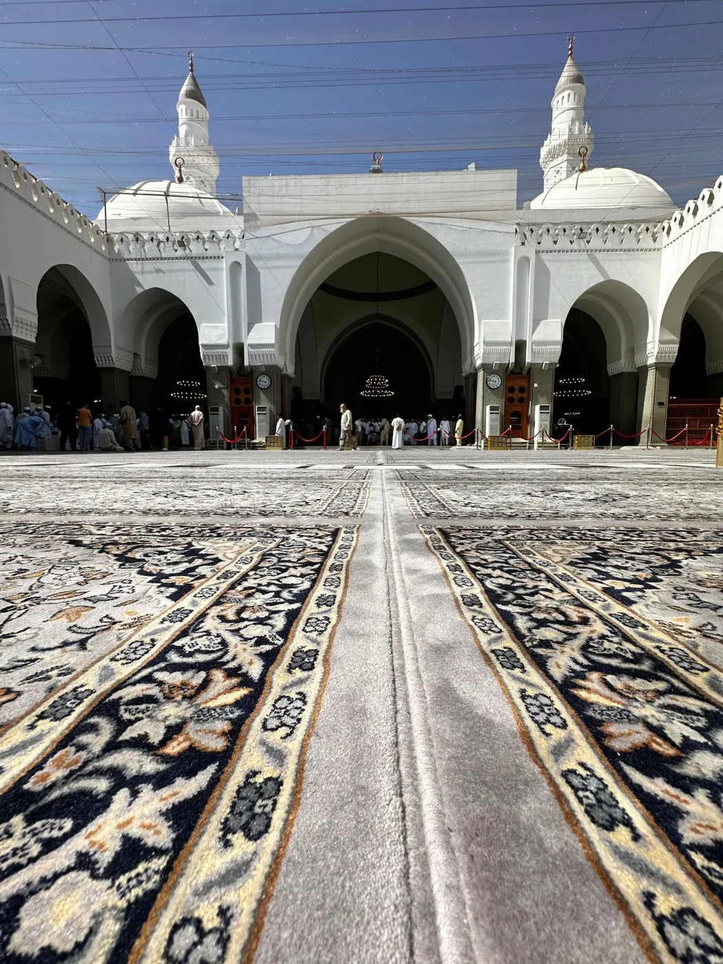 The white arches, domes and minarets of Masjid Quba seen from the carpeted courtyard