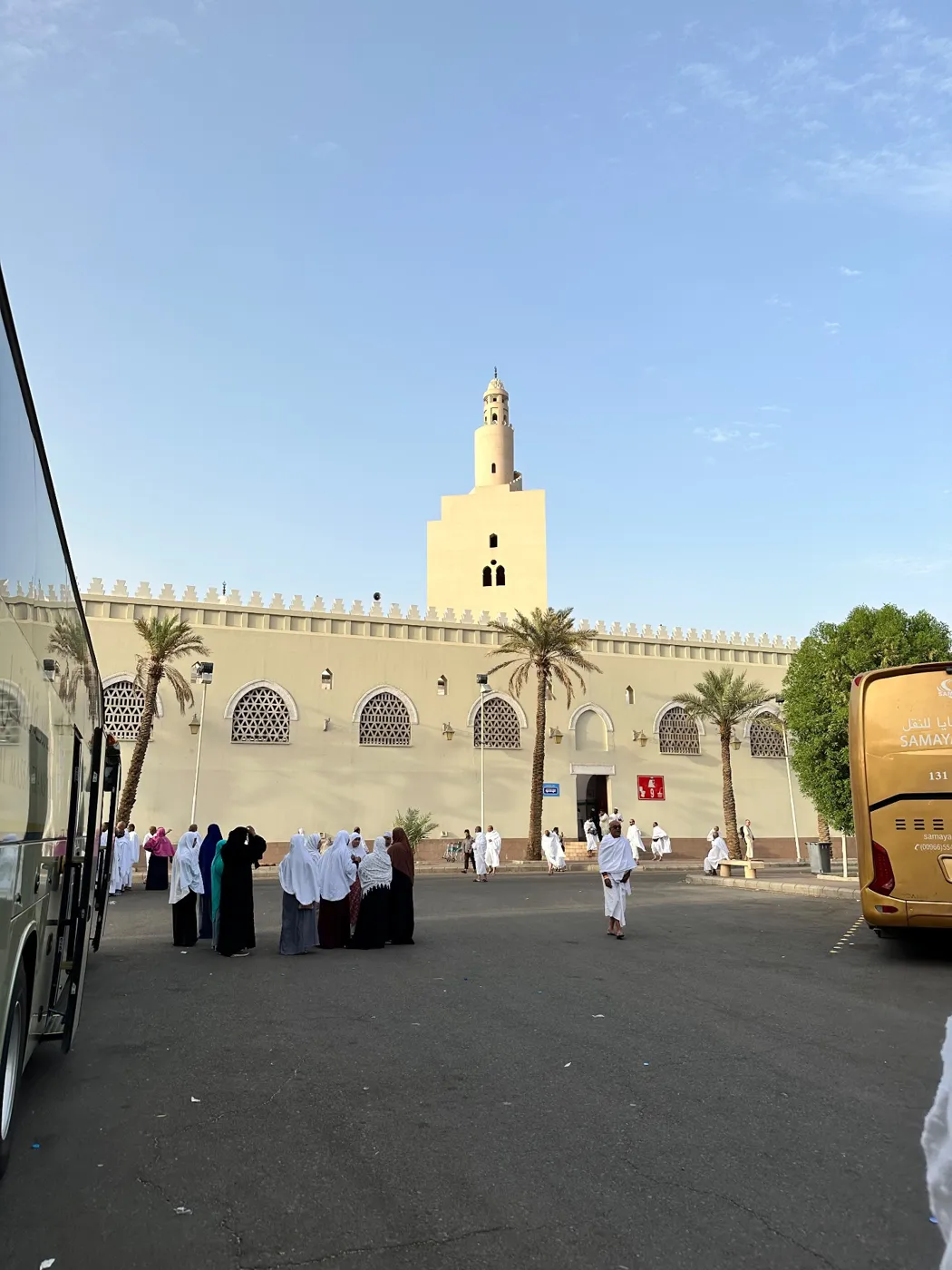 Pilgrims in Ihram outside the Miqat mosque near Madinah with its tall spiral minaret